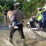 Polisi ini Bantu Dorong Sepeda Motor Warga dan Gendong Anak-anak Melintasi Banjir